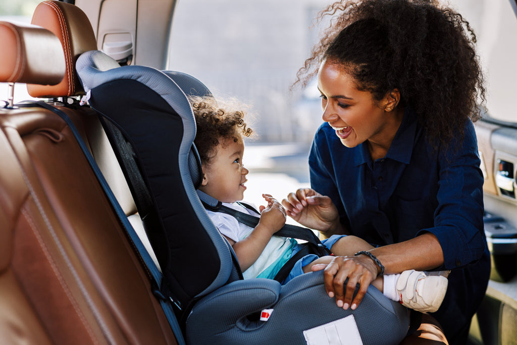 young mother securing her toddler in a car seat